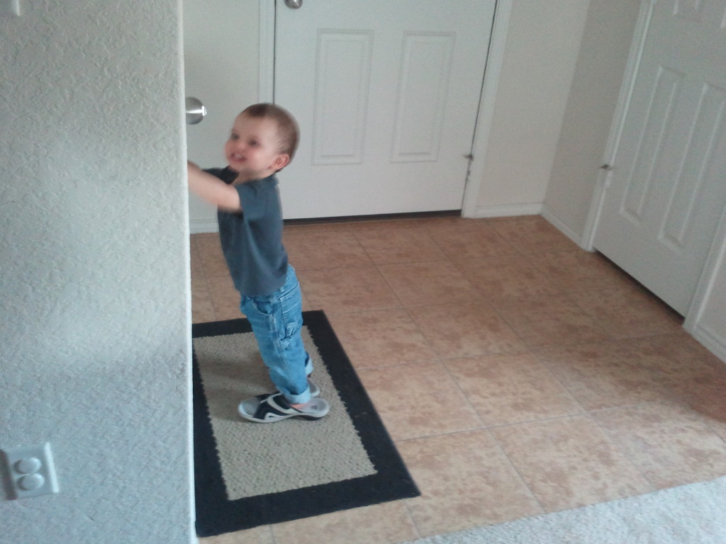 Seeing if Grandma's shoes make him tall enough to reach the door nob.