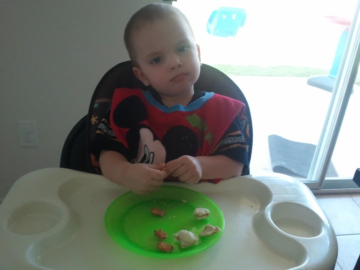 A preiceless expression as he enjoys a peanut butter sandwich and goldfish pretzel crackers